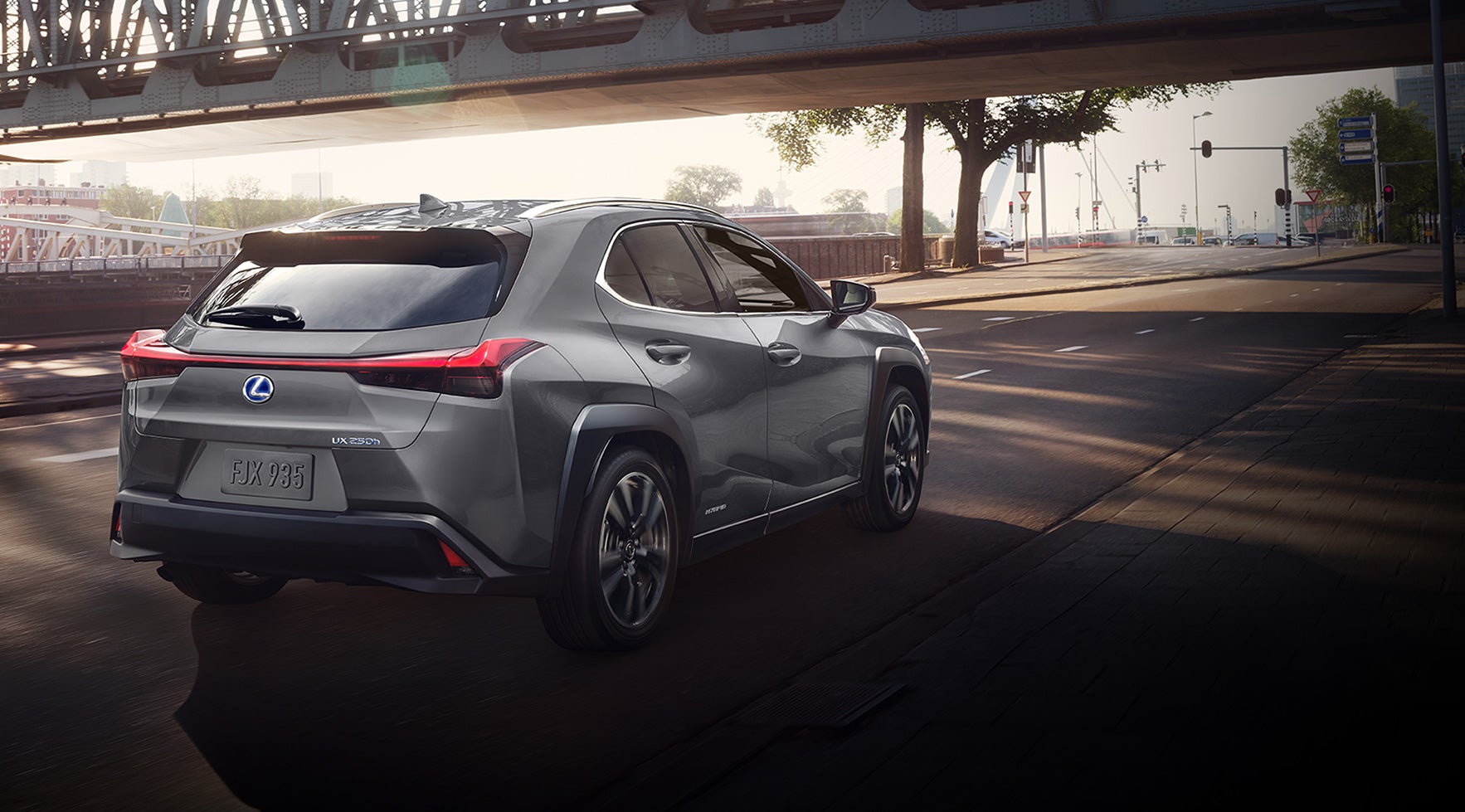 Lexus UX driving under a city bridge